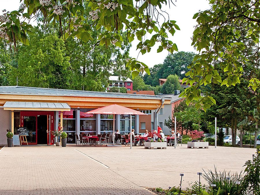 Wandelhalle Bad König mit Café-Pavillon, Sonnenschirmen und Gästen an einem Sommertag